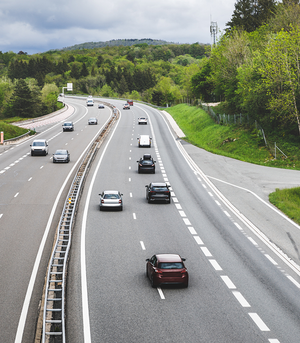 GettyImages-1366835828 1 A highway with cars driving on it and trees in the background.